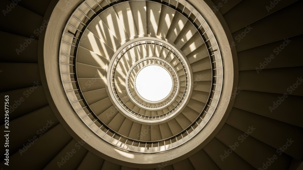 Obraz premium Worm's-eye view of a modern spiral staircase.