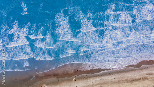 Cuadro en lienzo Vista aérea cenital de olas rompiendo en una playa de arena con personas lejanas