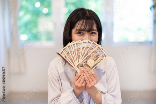 Foto Asian woman smiling while holding ten 10000 yen banknotes