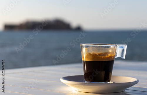 Espresso coffee cup on white wooden table against Mediterranean sea beach background in Al Hoceima Morocco