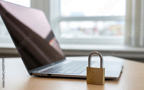Secure laptop computer with padlock security on desk for data protection.