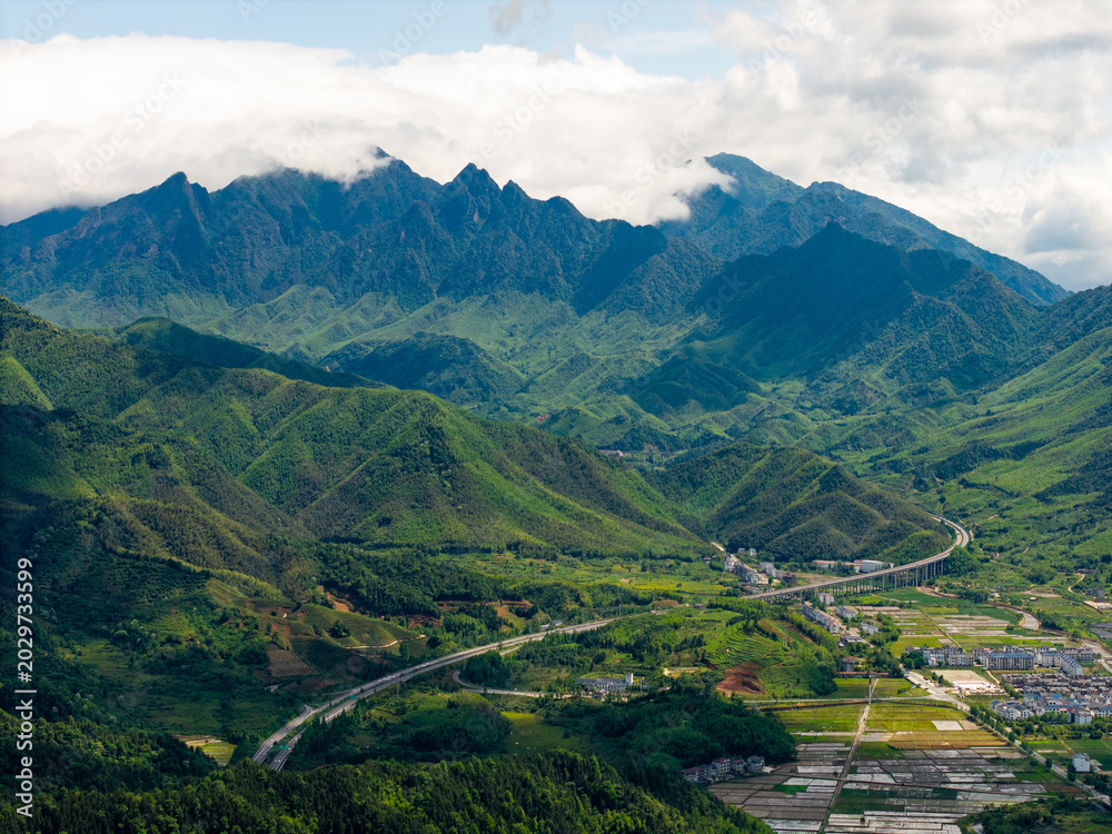 Fototapeta premium A scenic view shows the green mountains of Wuyi Mountain in Fujian China with a highway winding through the valley below