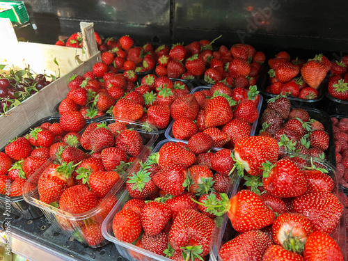Fresh strawberries and blueberries arranged in containers at a local market