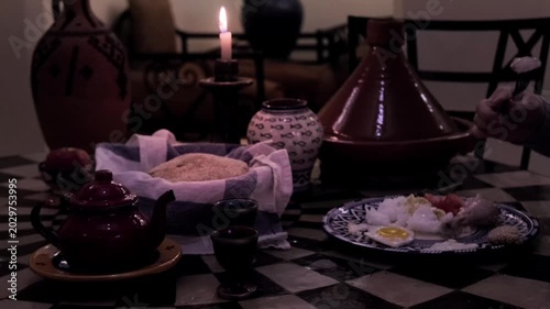 Traditional Moroccan table setting, featuring Terracotta tagine, bread, cakes, and tea, candle burning, cultural dining experience, Moroccan ceramic plates with traditional Moroccan patterns