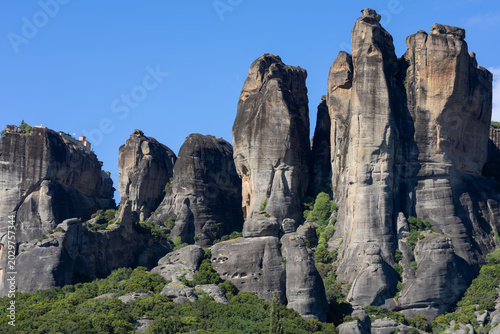 Photos towering conglomerate rock pillars of meteora in greece featuring the historic monastery of varlaam perched on a cliff edge under a clear blue mediterranean sky