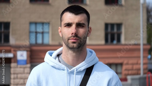 Photos Portrait of young confident bearded man in casual clothing with cityscape background