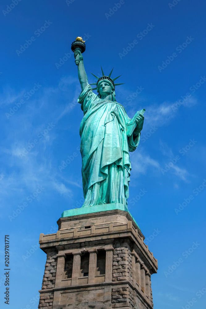 Fototapeta premium Low angle view of the Statue of Liberty in New York City with clear blue sky and dramatic perspective.