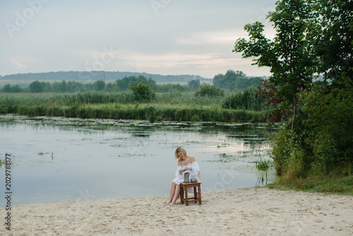 Woman sculpting clay by river wetlands at sunrise