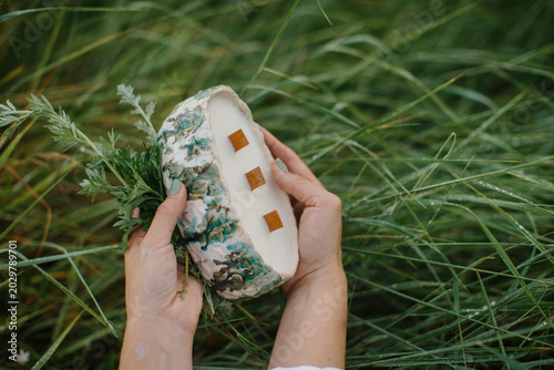 Obraz na płótnie Hands holding natural artisanal candle in dewy grass