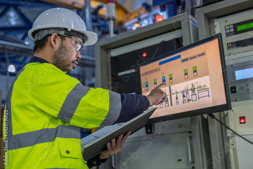 Professional engineer monitoring industrial automation system on digital screen in high-tech factory control room. Concept of smart manufacturing, technical data analysis, and modern engineering.