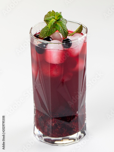 Foto Refreshing berry cocktail with mint and ice in a faceted glass, isolated on a white background