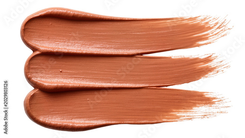 Foto Three copper-colored makeup swatches with metallic sheen, isolated on transparen