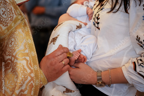 Tableau sur toile Priest anointing baby foot during Orthodox baptism
