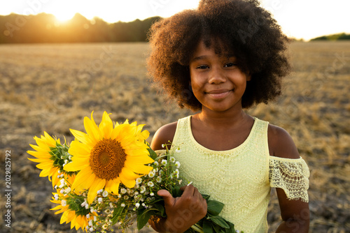 Pretty young african girl in a sunflowers field in bloom 