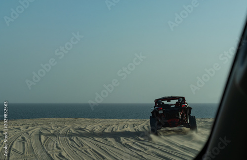 Tableau sur toile Action motion blur of a dune buggy driving along a soft focus coastal ridge at Khor Al Adaid