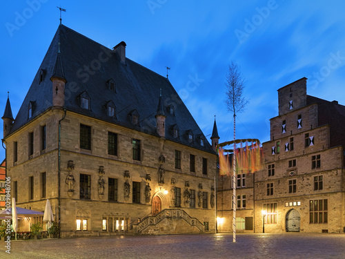 Osnabruck, Germany. Historical Market Square with Old Town Hall, Stadtwaage (city weighhouse or weighing house) and erected Maypole in twilight.