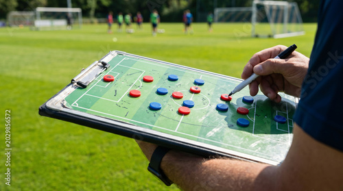 Coach drawing strategy on board at soccer field