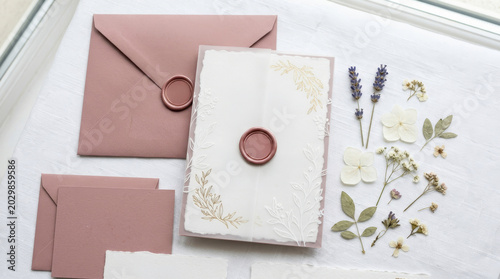 Elegant stationery featuring pink envelopes and a decorative wax seal, accompanied by dried flowers for a romantic touch.
