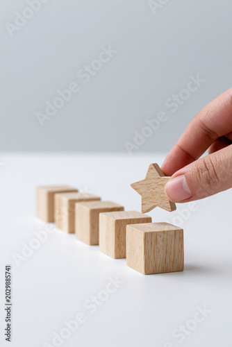 Hand place wooden star on block, concept of best service, rating, or award