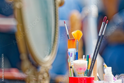 Bild auf Leinwand Variety of colorful makeup brushes and tools in a red container on vanity table