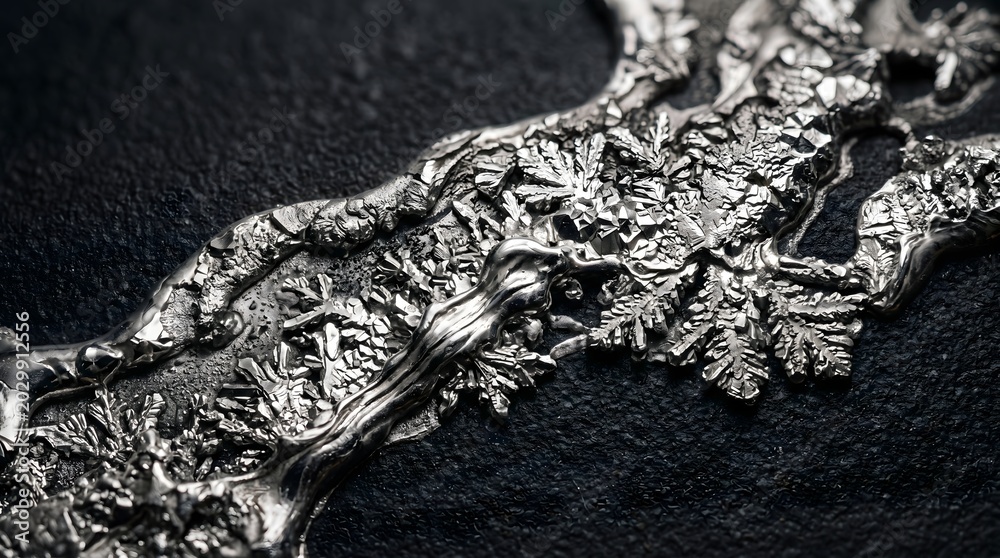 Fototapeta premium Close up macro shot of metallic silver crystal growth showing intricate dendritic patterns on a dark textured surface
