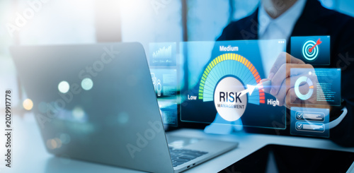 Photos Businessman using laptop with glowing risk meter, data charts and tech icons for identifying, assessing, and mitigating future occurrences