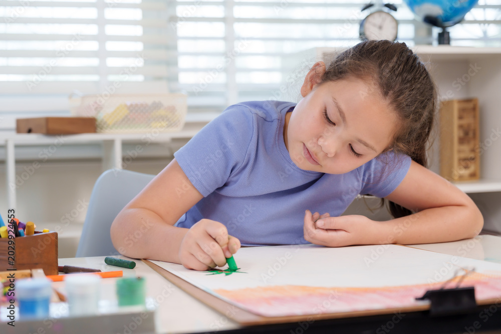 Naklejka premium Caucasian girl preteen coloring large artwork paper green crayon during elementary classroom art lesson concentrating creativity practice childhood learning study education discipline