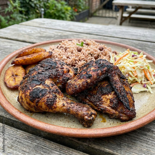 Obraz na plátně A plate of grilled jerk chicken with rice and vegetables outdoors