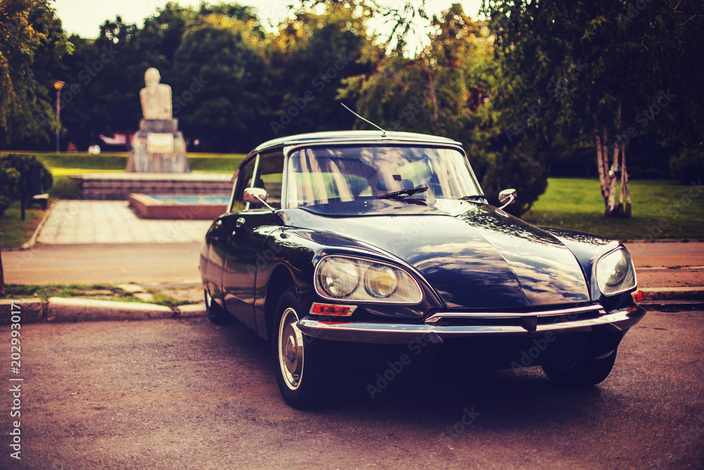 Fototapeta premium Vintage luxury car parked in urban park setting