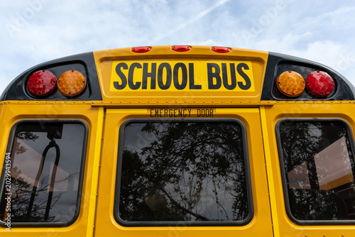 Back view of a classic yellow school bus with emergency door and lights