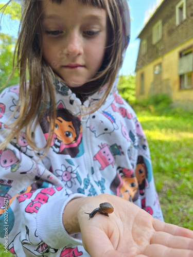 Child holding a small snail on her hand in Latvia