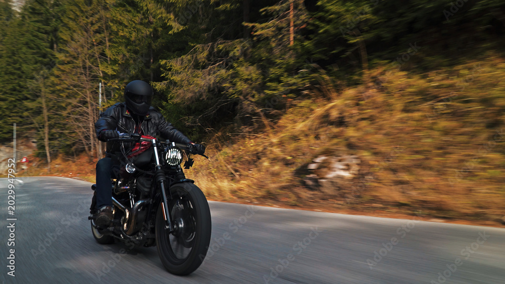 Fototapeta premium Motorcycle rider speeding through mountain forest road