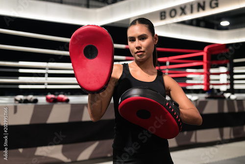 Female Boxing Coach Holding Red Punch Mitts in Ring
