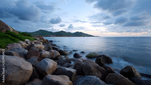 A dramatic seascape features a vast expanse of water meeting a rugged coastline under a moody cloudy sky