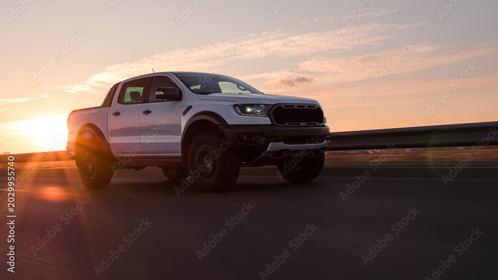 Naklejka premium White pickup truck driving on highway during sunset