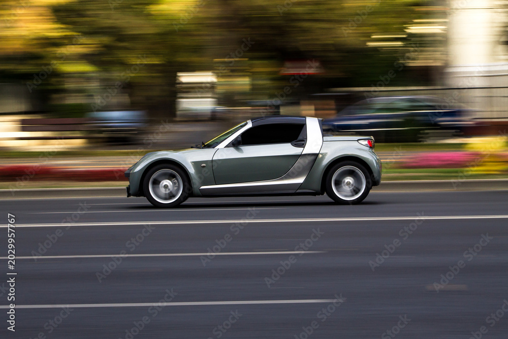 Obraz premium Silver sports car moving fast on city street
