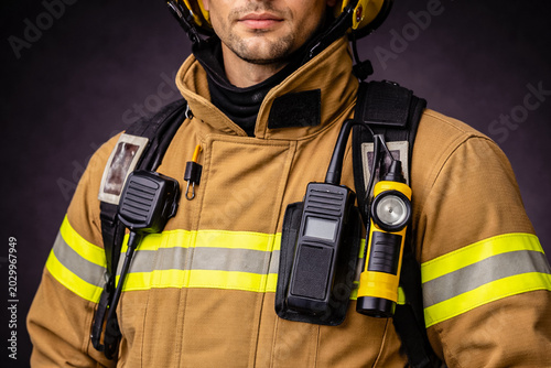 Close-up of a firefighter in protective uniform with walkie-talkie and flashlight gear