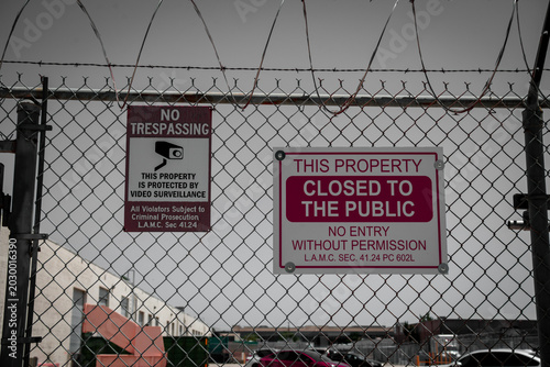 Schilderij op canvas No Trespassing and Closed to Public signs on a chain link fence with barbed wire