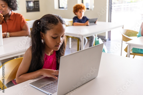 Foto Classroom children with instructor using silver laptop and tablet in bright room