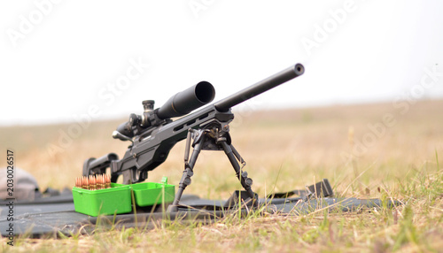 Bild auf Leinwand Front view of precision bolt-action rifle with ammunition box on outdoor shootin