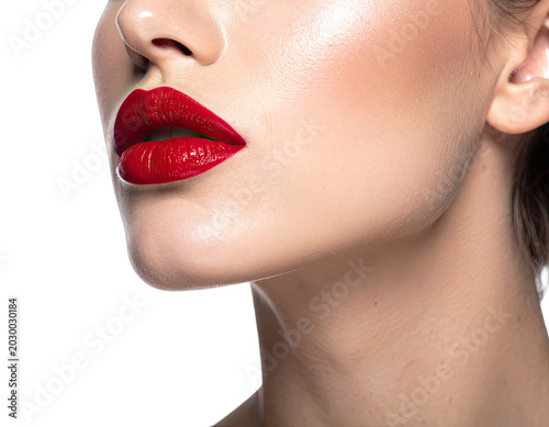 A close-up shot of a woman's face featuring bold red lipstick against a black background.