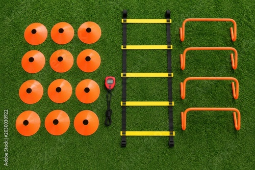 Assortment of soccer training equipment including cones, hurdles, and an agility ladder on turf