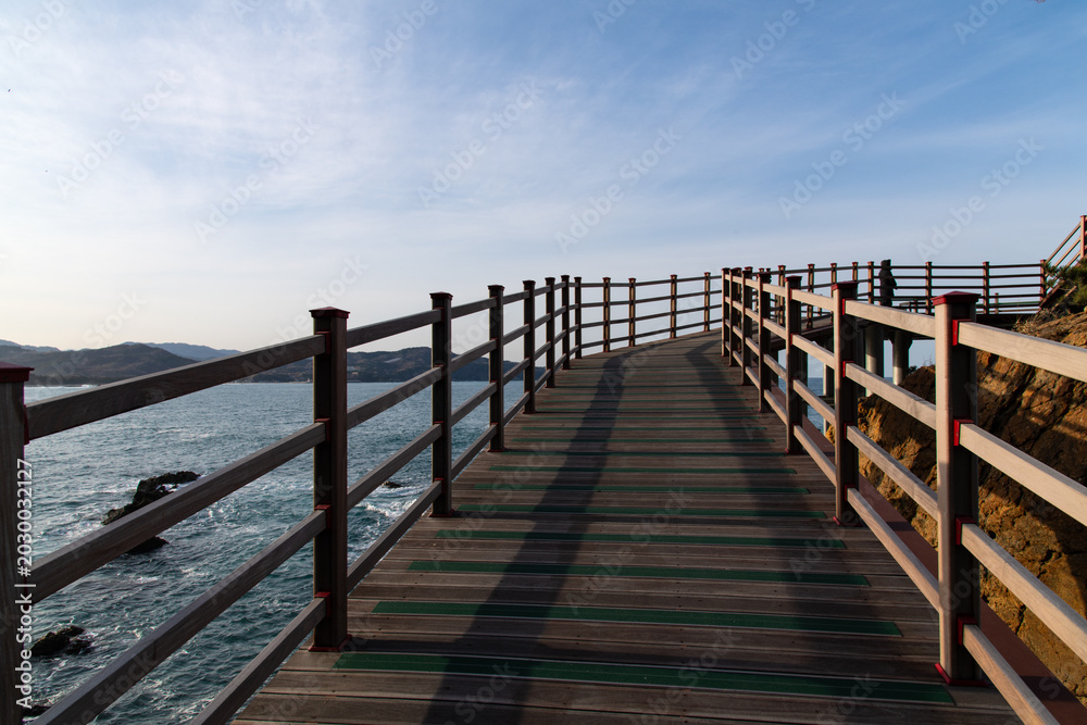 Fototapeta premium Wooden Coastal Boardwalk Overlooking Blue Ocean Horizon