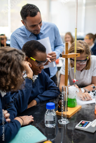 Schilderij op canvas Diverse schoolchildren and a male teacher observe a chemistry experiment