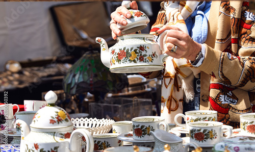 Quadro su tela Vintage porcelain teapot held by a woman in a patterned cardigan at a flea marke