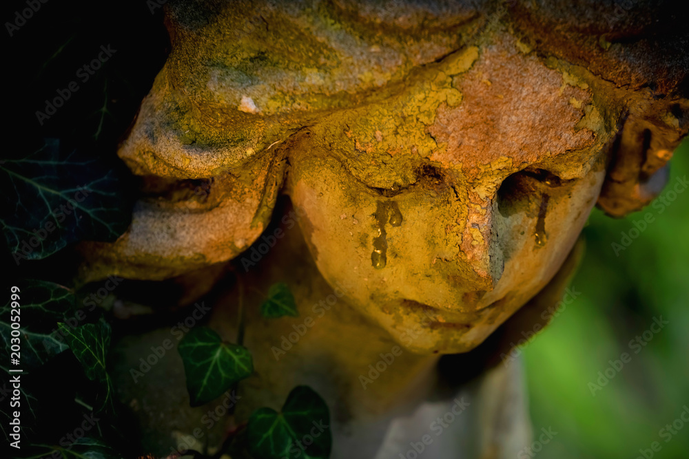 Fototapeta premium Weeping angel statue with tears in warm mystical light