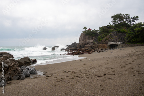 Scenic view of crashing waves at Katsurahama Beach with a cliffside shrine, Kochi, Japan