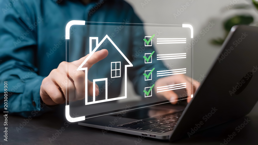 Fototapeta premium Hand holding digital house icon over laptop with real estate interface on screen