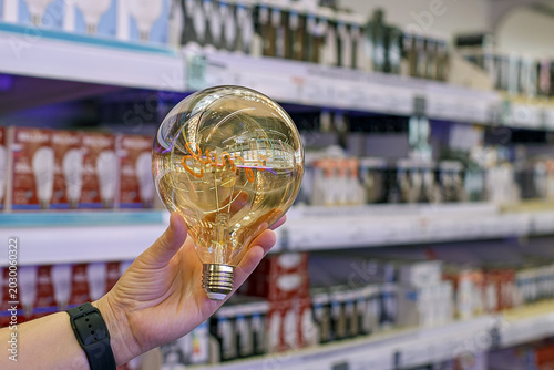 Obraz na plátně LED lamp with a filament in the hands of a customer in a lighting equipment store