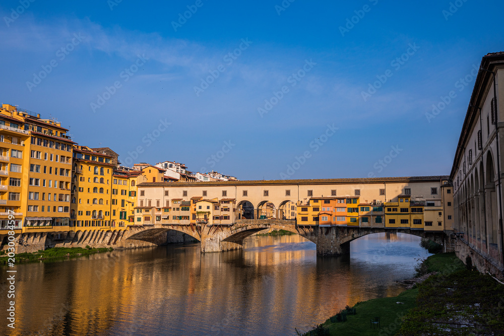 Fototapeta premium Sunlit Ponte Vecchio over Arno River in Florence, Italy